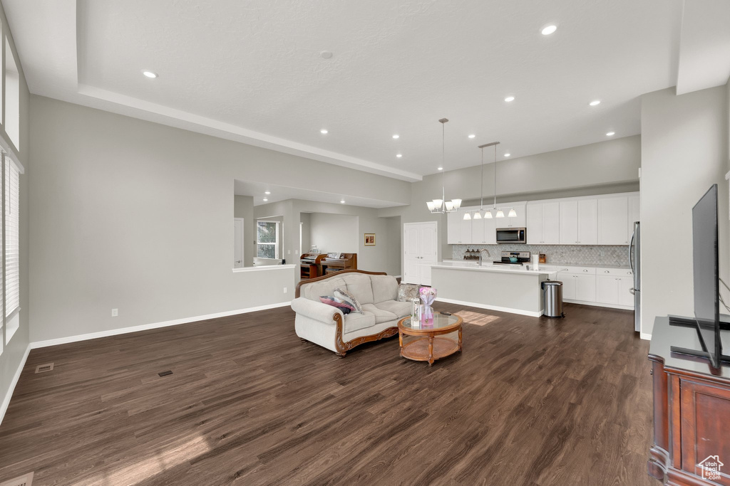 Living area featuring a chandelier, dark wood finished floors, recessed lighting, and baseboards
