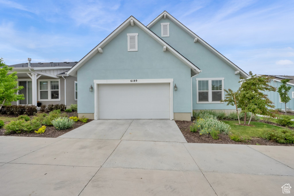 Traditional home with a garage, driveway, and stucco siding