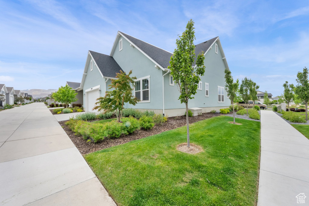 View of side of property featuring a yard, a residential view, stucco siding, and roof with shingles