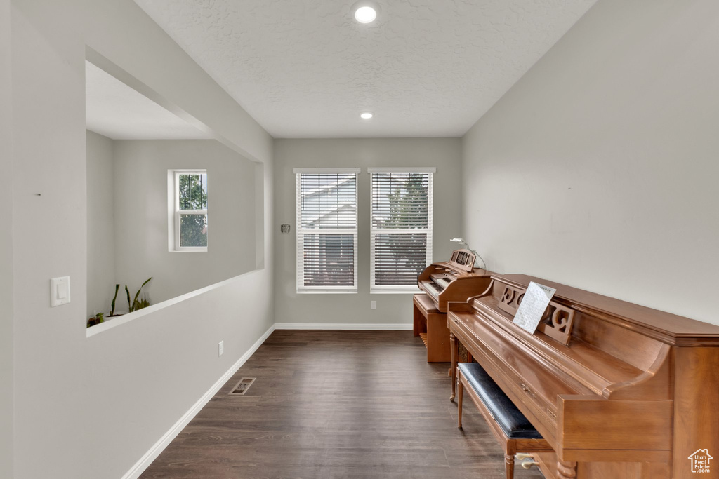 Sitting room featuring dark wood-style floors, baseboards, recessed lighting, and a textured ceiling