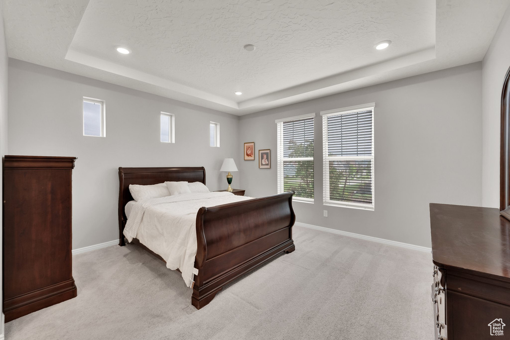 Bedroom featuring a raised ceiling, baseboards, light colored carpet, recessed lighting, and a textured ceiling
