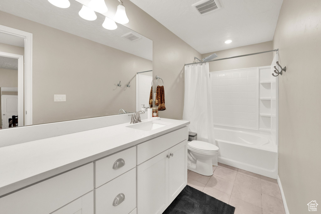 Full bathroom with tile patterned floors, toilet, shower / bathtub combination with curtain, and vanity