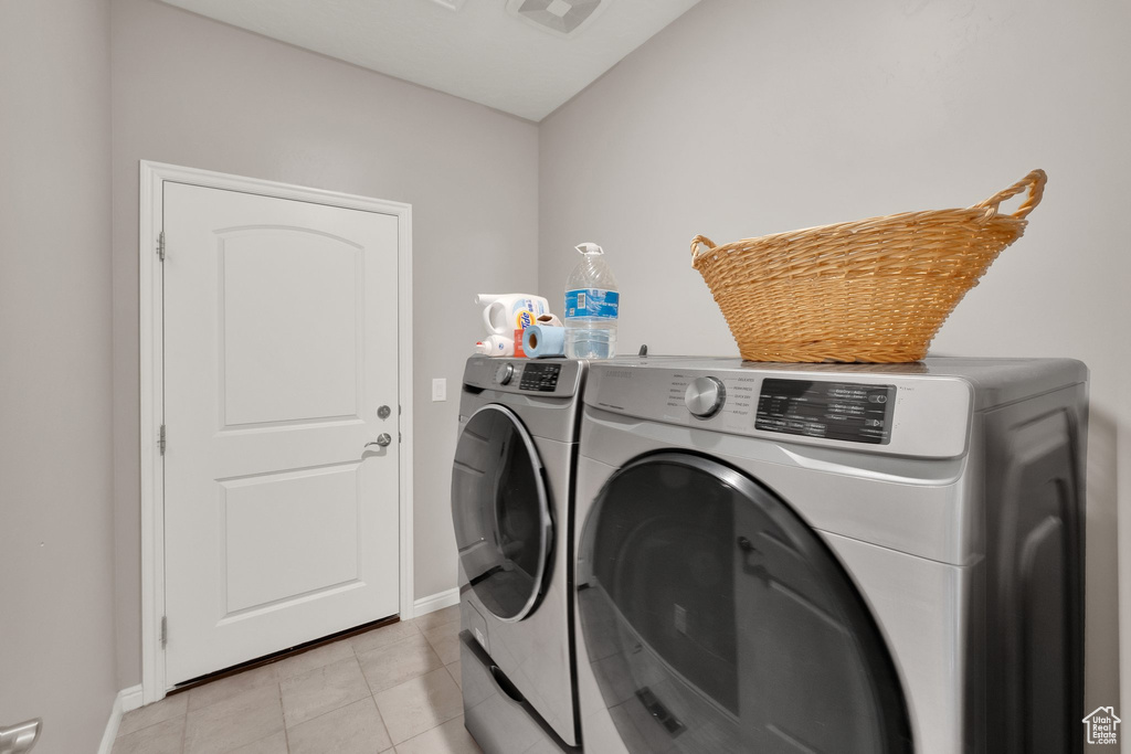 Laundry area with washer and dryer, baseboards, and light tile patterned flooring