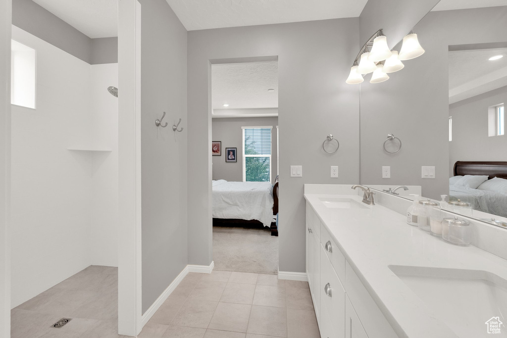 Bathroom featuring connected bathroom, baseboards, tile patterned flooring, double vanity, and recessed lighting