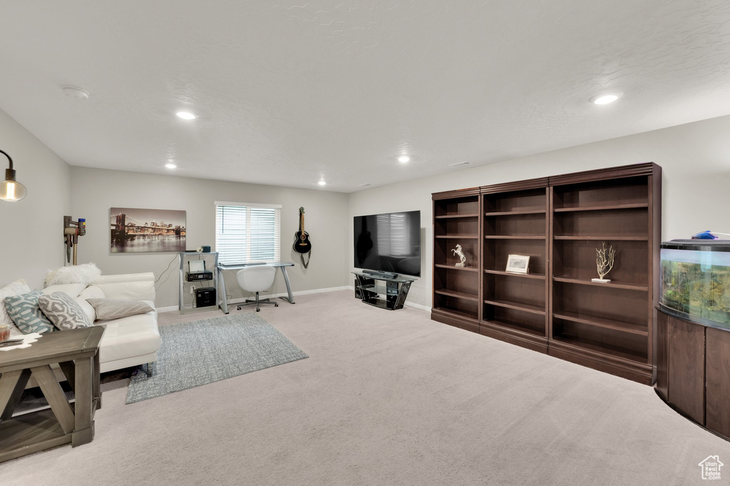Carpeted living area with recessed lighting and baseboards