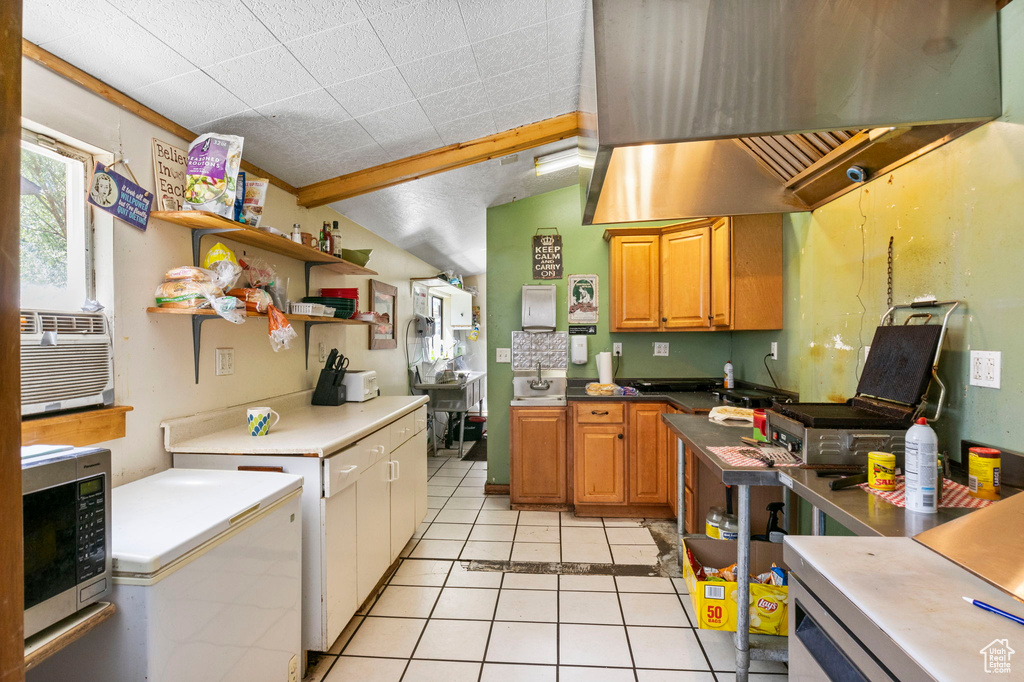 Kitchen with cooling unit, island exhaust hood, light tile patterned floors, and lofted ceiling with beams