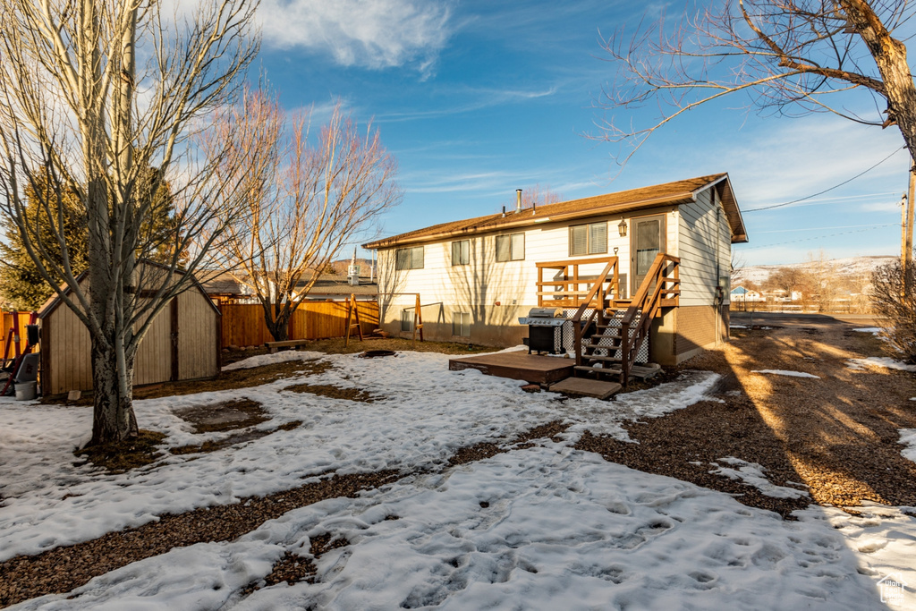 Snow covered house featuring a storage shed