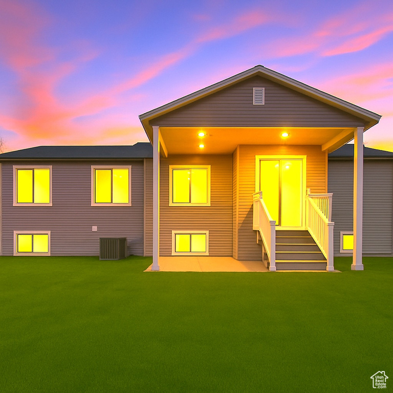 Back of property at dusk featuring a lawn