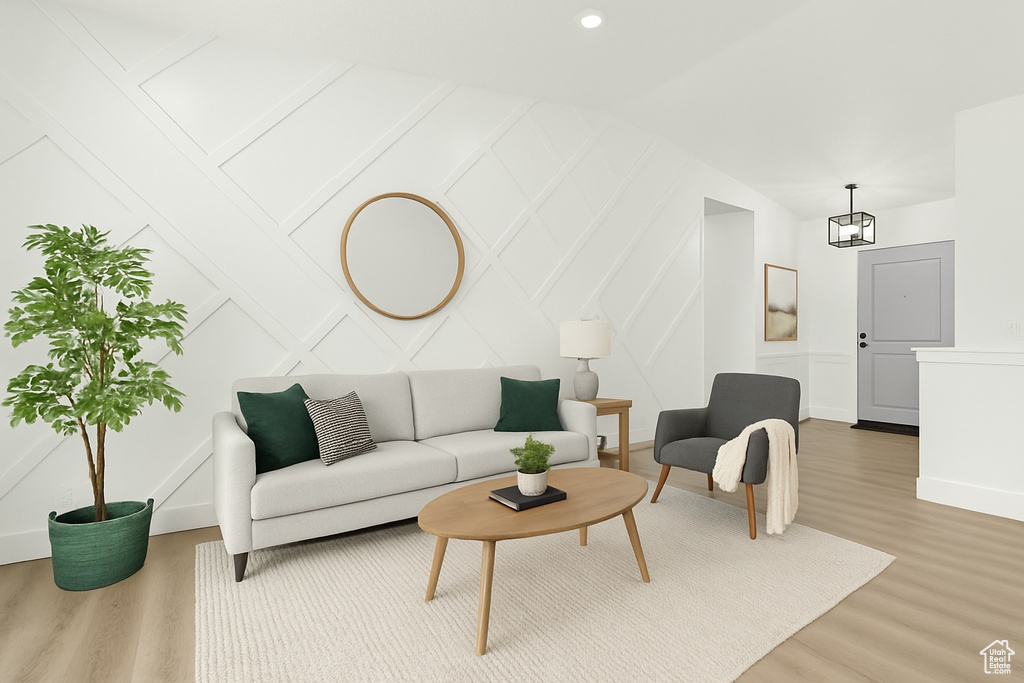 Living area with baseboards, a decorative wall, and wood finished floors