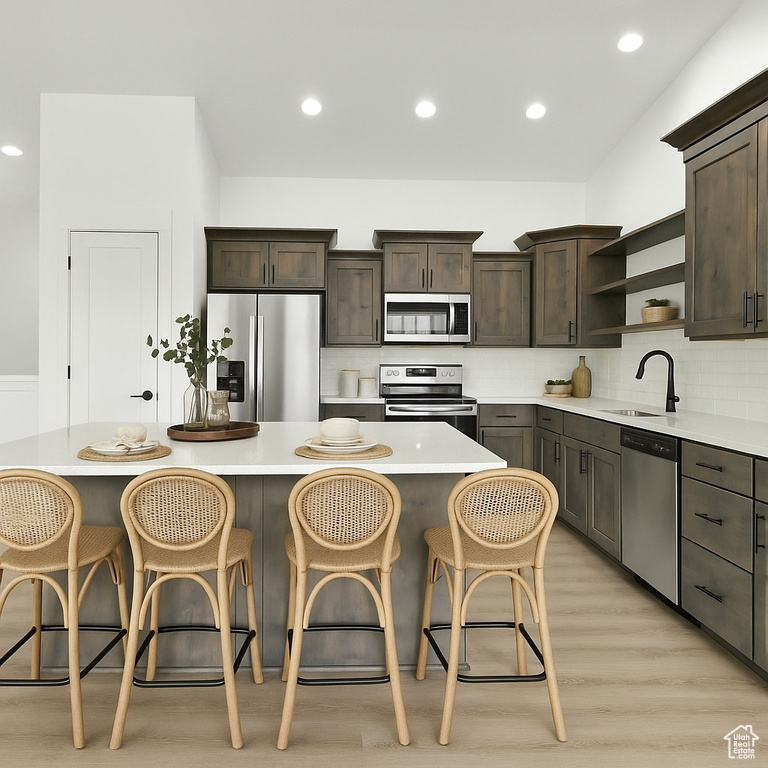 Kitchen featuring open shelves, dark brown cabinets, a sink, light countertops, and stainless steel appliances