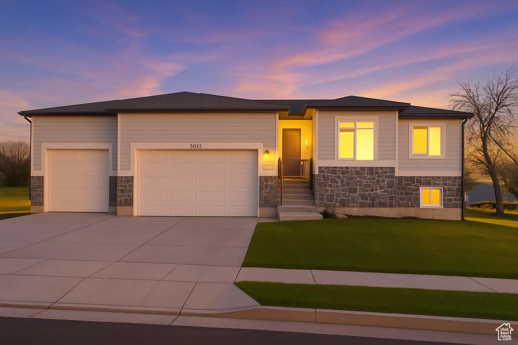 Prairie-style house featuring a garage, concrete driveway, a front yard, and stone siding