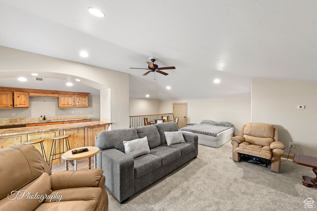 Carpeted living room with ceiling fan and sink