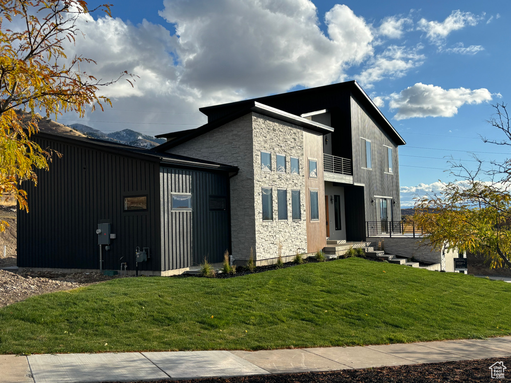 View of side of property featuring a balcony and a lawn