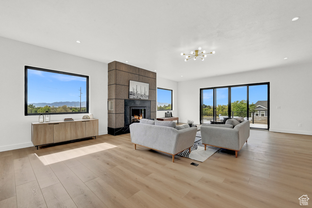 Living room featuring a fireplace, an inviting chandelier, and light hardwood / wood-style flooring