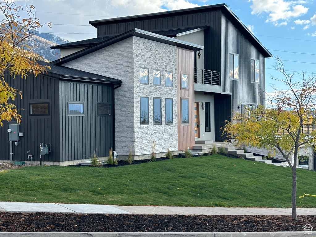 View of side of home with a balcony and a lawn