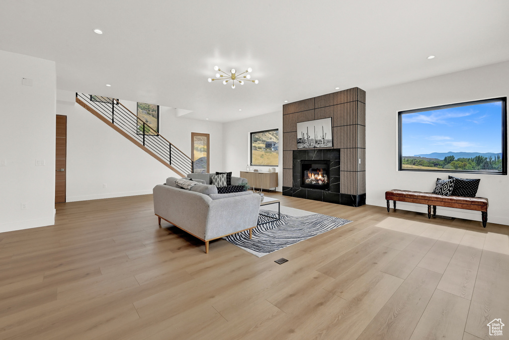 Living room with a tiled fireplace, light hardwood / wood-style floors, and a chandelier