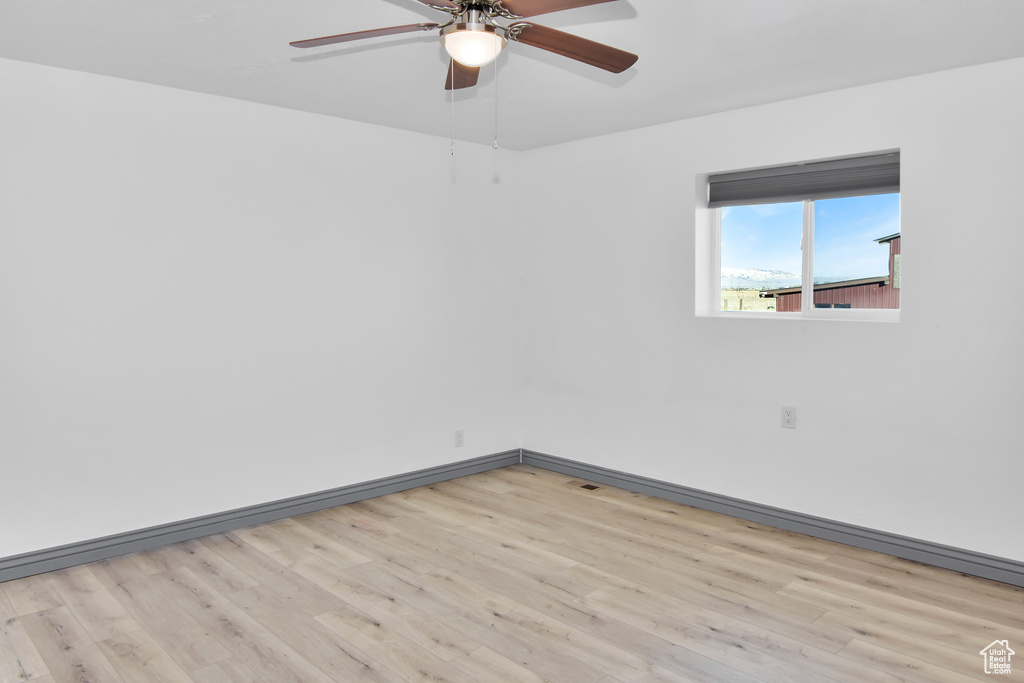 Empty room with ceiling fan and light hardwood / wood-style flooring