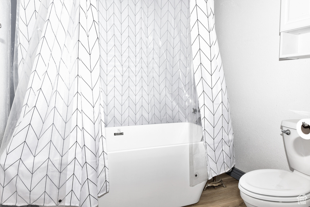 Bathroom featuring shower / bath combo, toilet, and hardwood / wood-style flooring