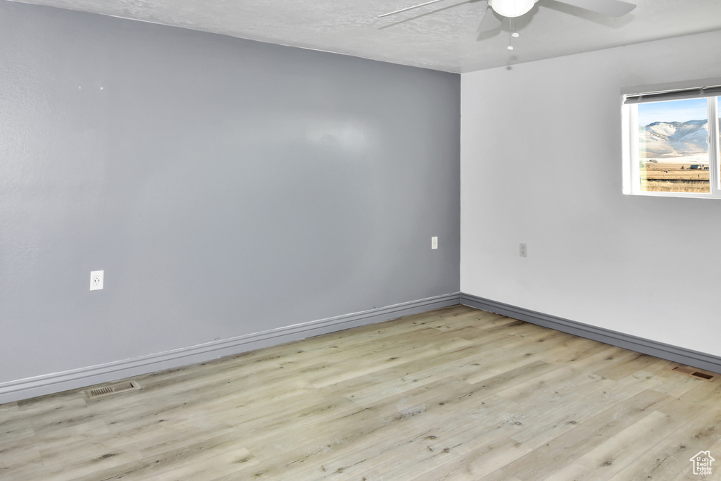 Unfurnished room featuring ceiling fan, light wood-type flooring, and a textured ceiling