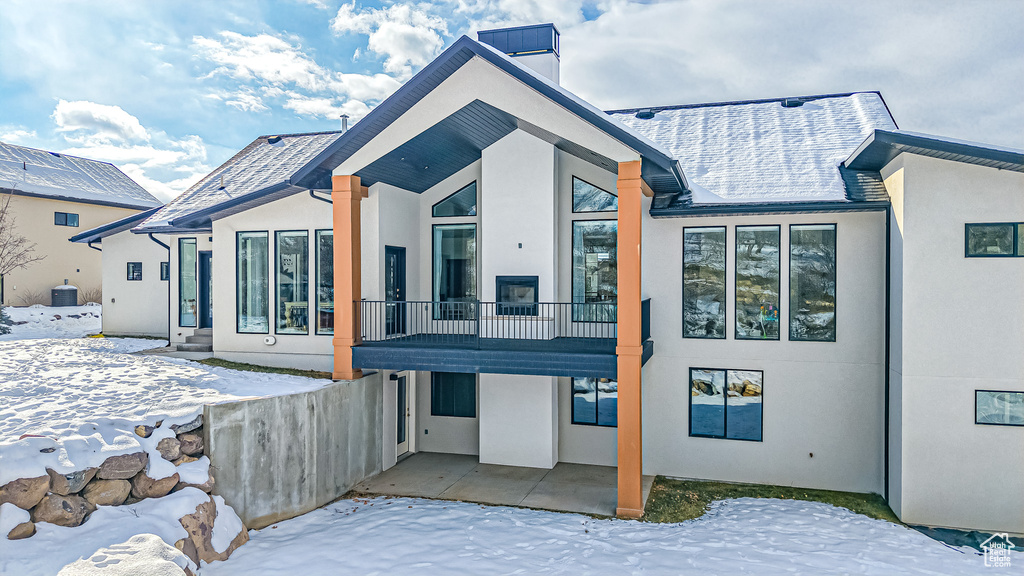 Snow covered property with a balcony and a patio