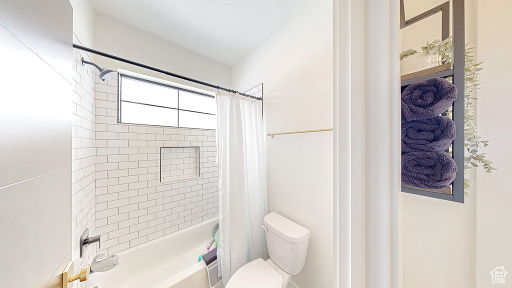 Bathroom featuring toilet and shower / bathtub combination with curtain