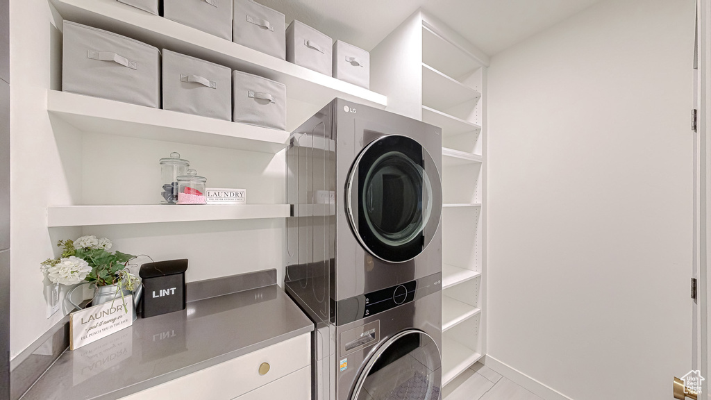 Washroom featuring stacked washer / dryer and light tile patterned flooring