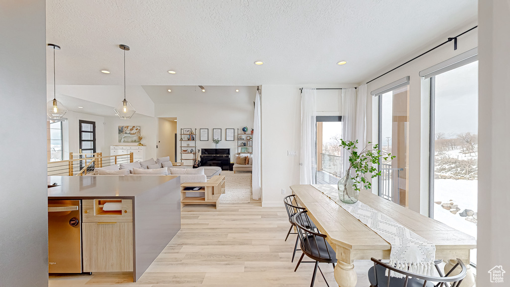 Kitchen with stainless steel dishwasher, decorative light fixtures, a textured ceiling, and light wood-type flooring