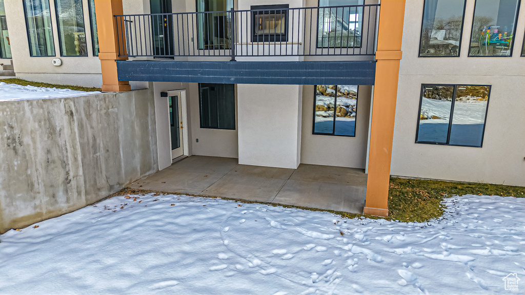 Snow covered patio featuring a balcony