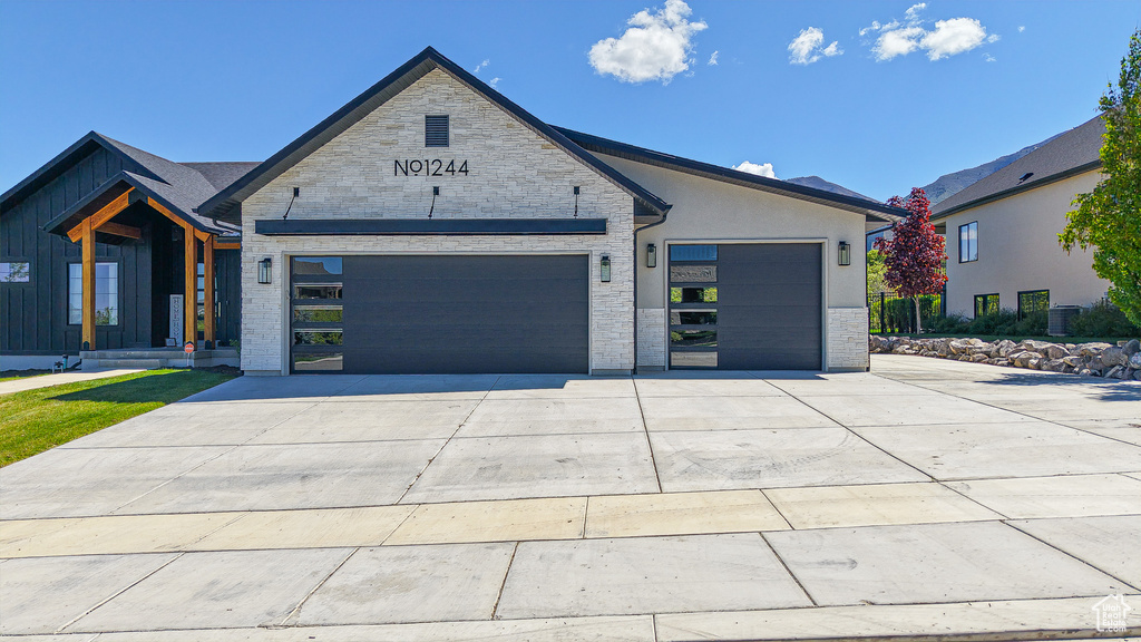View of front of house with concrete driveway, a garage, and stone siding