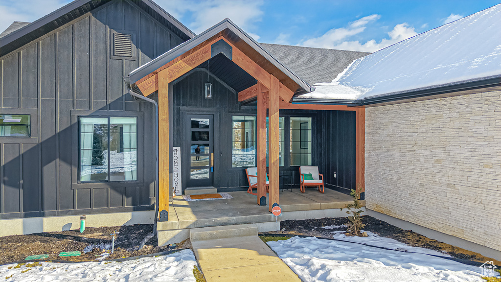 Snow covered property entrance with a porch