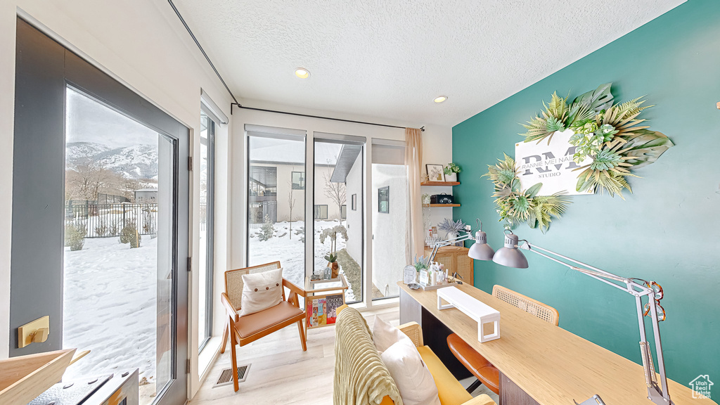 Office area with light hardwood / wood-style floors and a textured ceiling