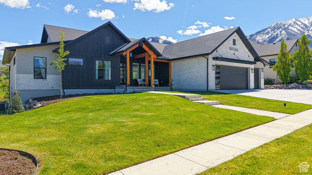 View of front of house with concrete driveway, a front lawn, a garage, and a mountain view