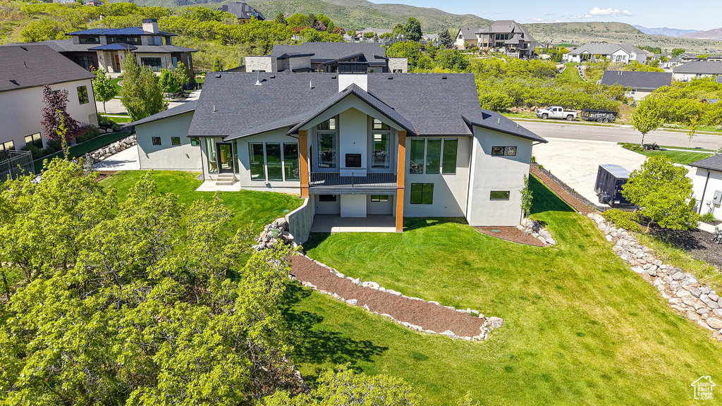Back of property featuring stucco siding, a mountain view, a residential view, and roof with shingles