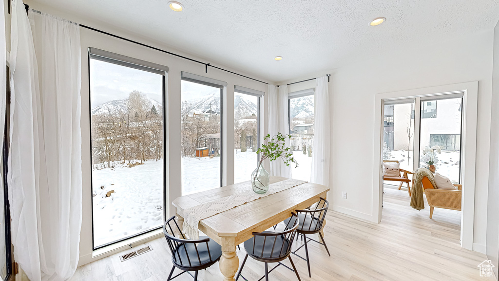 Dining space with a textured ceiling and light hardwood / wood-style floors