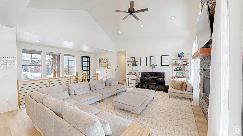 Living room featuring high vaulted ceiling, ceiling fan, and light hardwood / wood-style floors