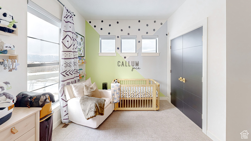 Bedroom with light colored carpet and a nursery area