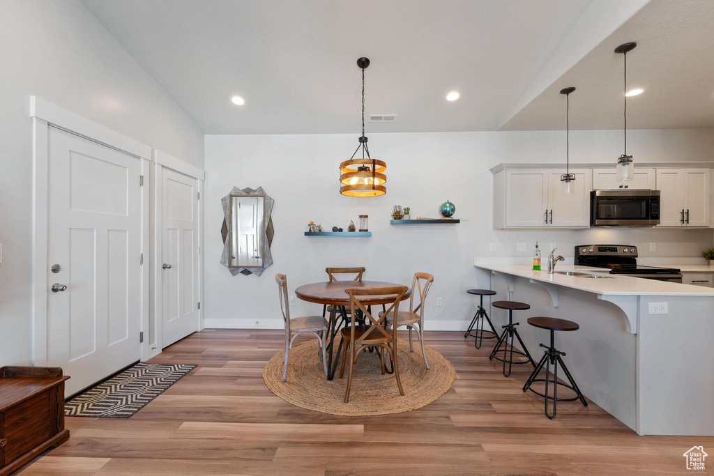 Dining room featuring light hardwood / wood-style floors, lofted ceiling, and sink
