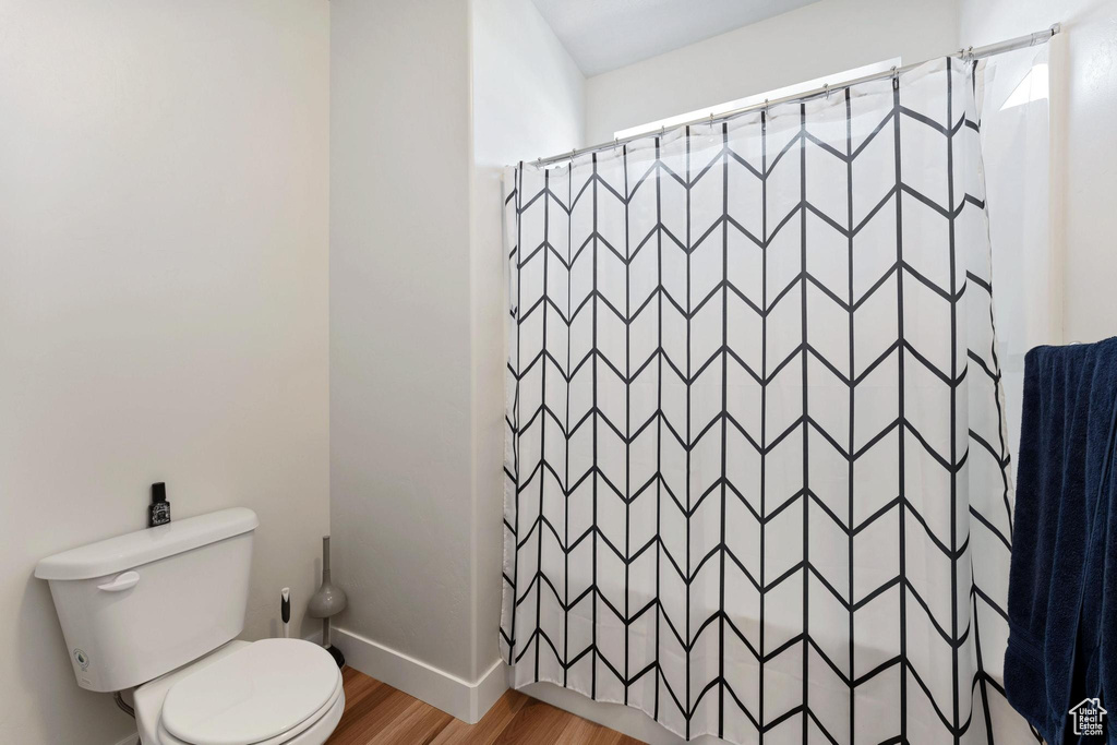 Bathroom featuring toilet, wood-type flooring, and walk in shower