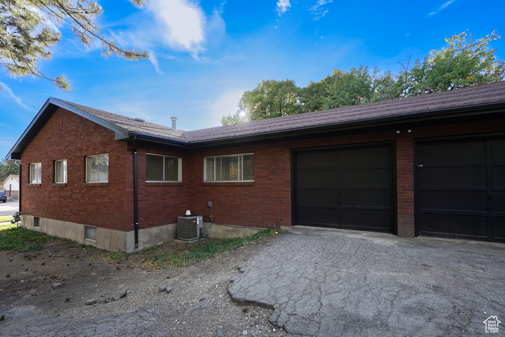 View of side of home with central air condition unit and a garage