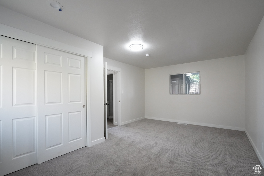 Unfurnished bedroom with a closet and light carpet