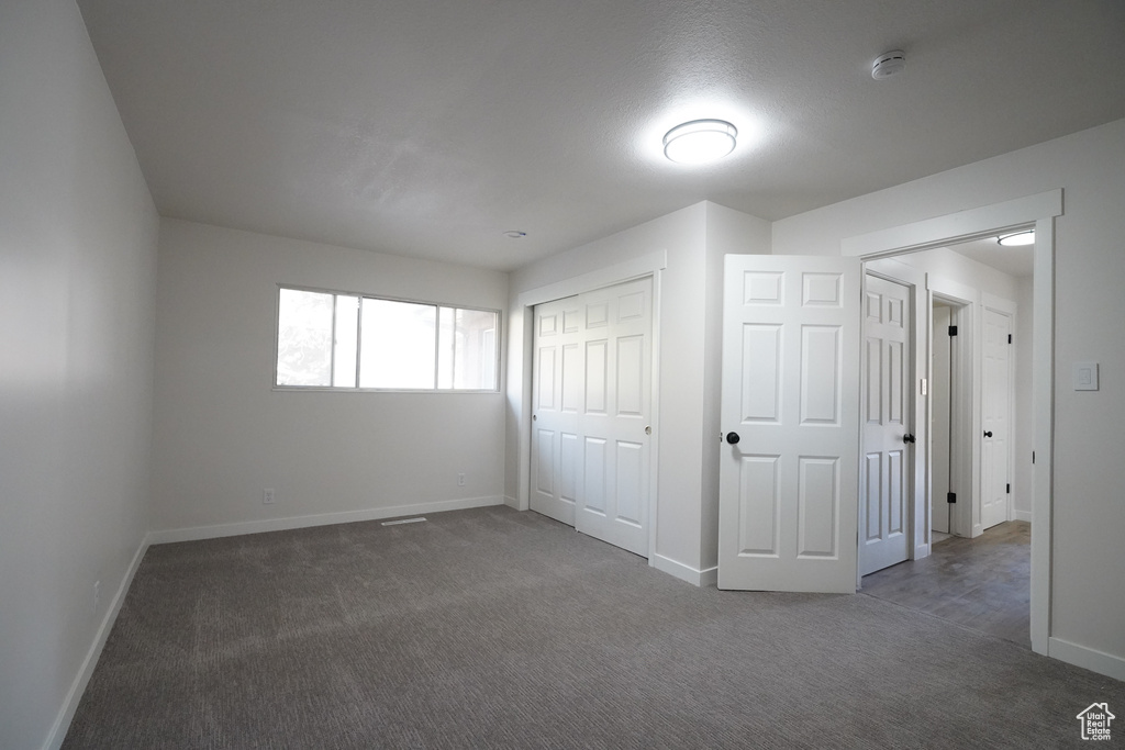 Unfurnished bedroom featuring a closet and dark carpet