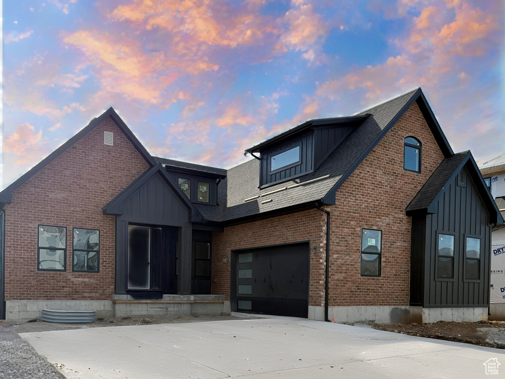 View of front of house featuring brick siding, driveway, and board and batten siding