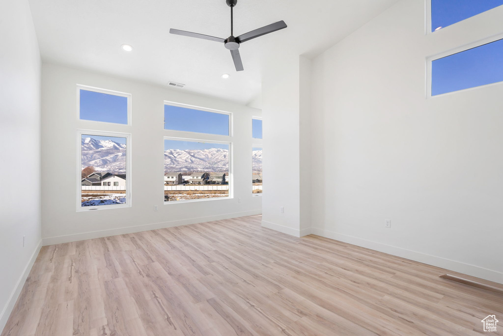 Unfurnished living room with a high ceiling, ceiling fan, and light hardwood / wood-style flooring