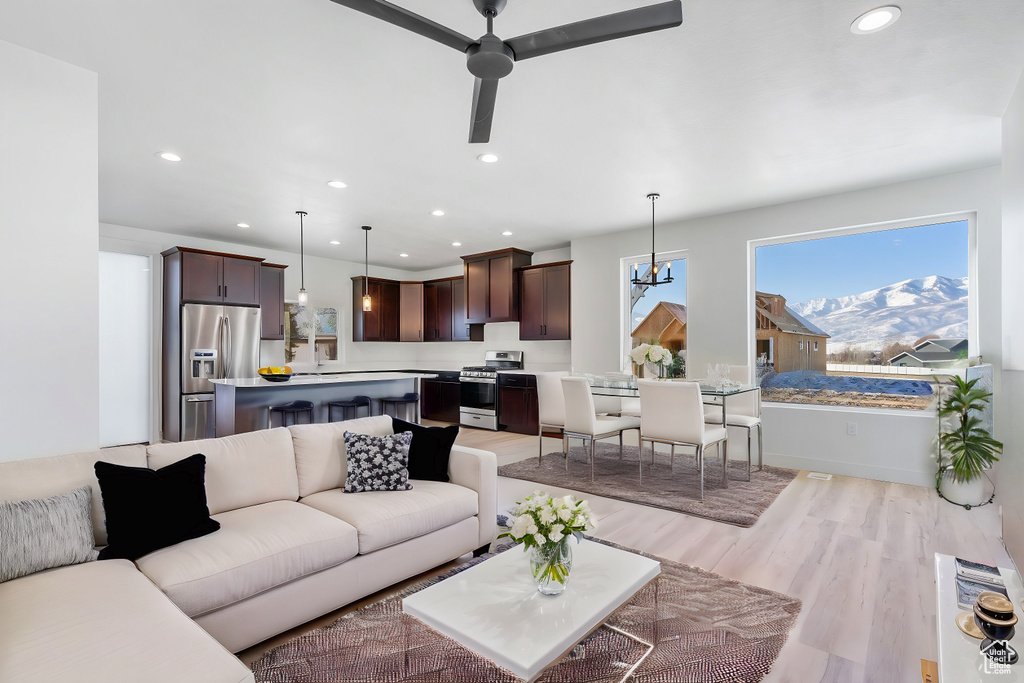 Living room featuring ceiling fan with notable chandelier and light hardwood / wood-style flooring