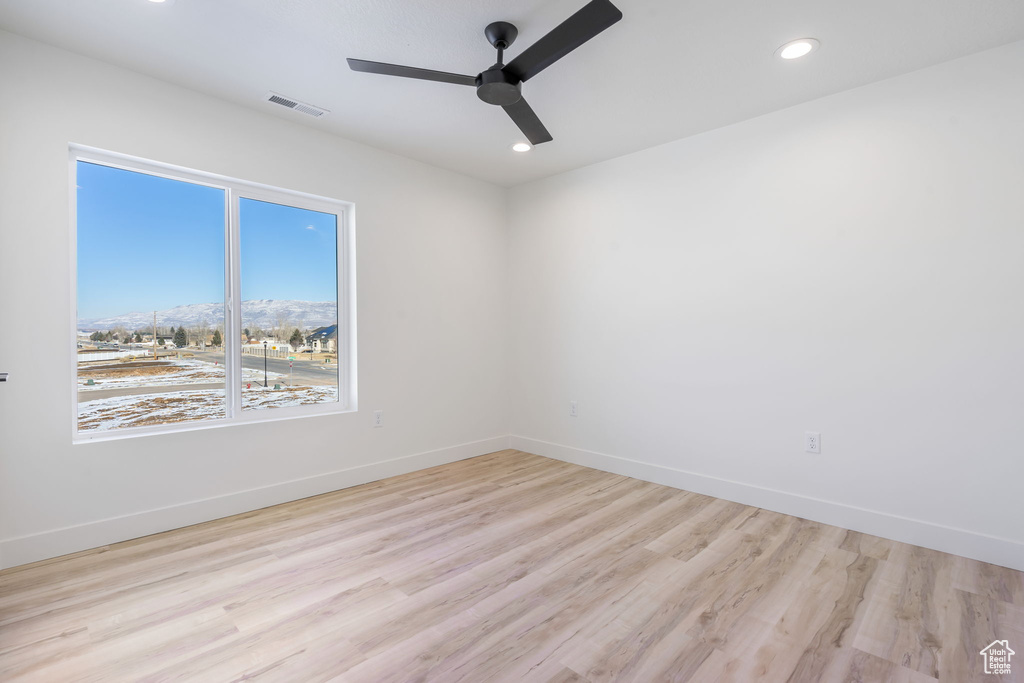 Empty room featuring ceiling fan, light wood-type flooring, and a mountain view