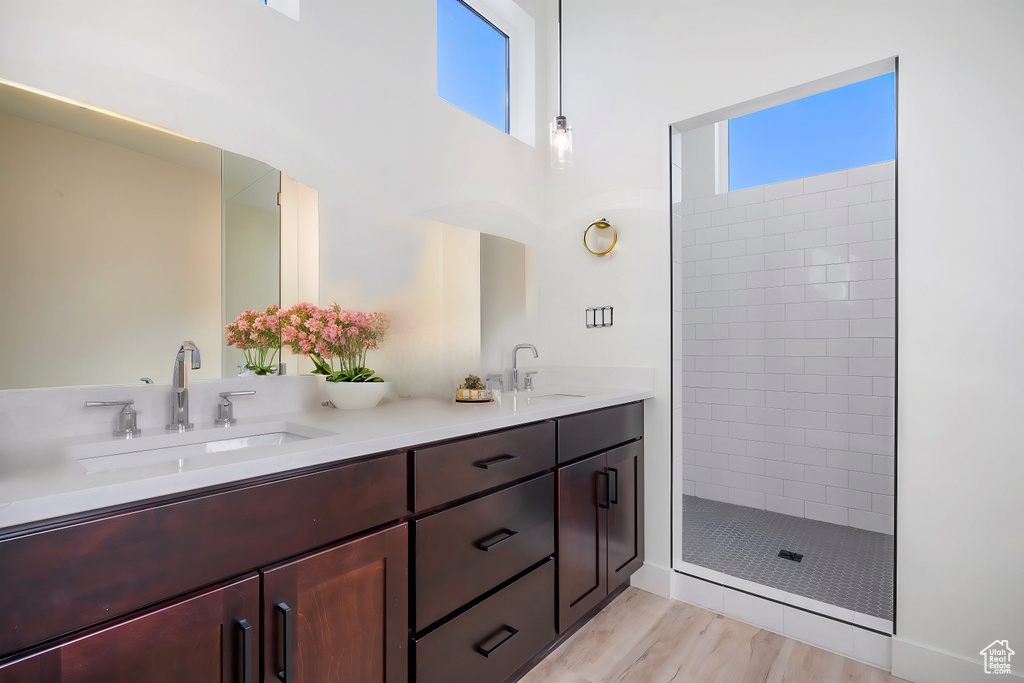 Bathroom featuring hardwood / wood-style floors, vanity, and a tile shower