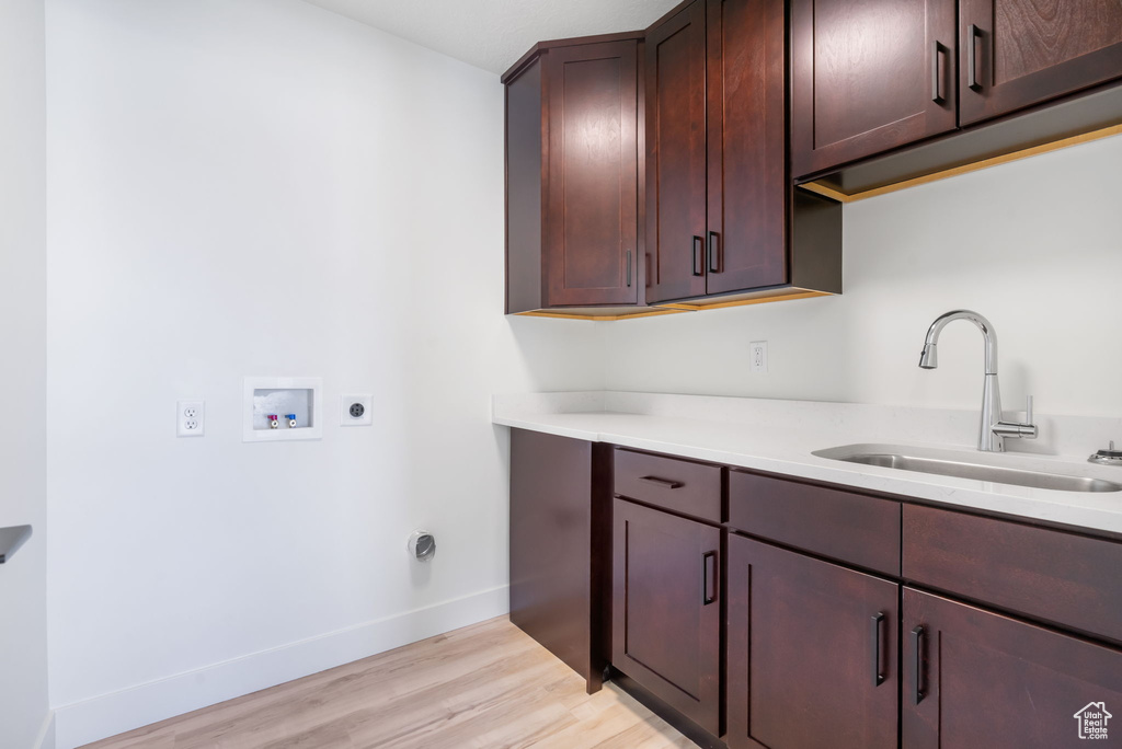 Washroom featuring cabinets, hookup for a washing machine, hookup for an electric dryer, sink, and light hardwood / wood-style flooring