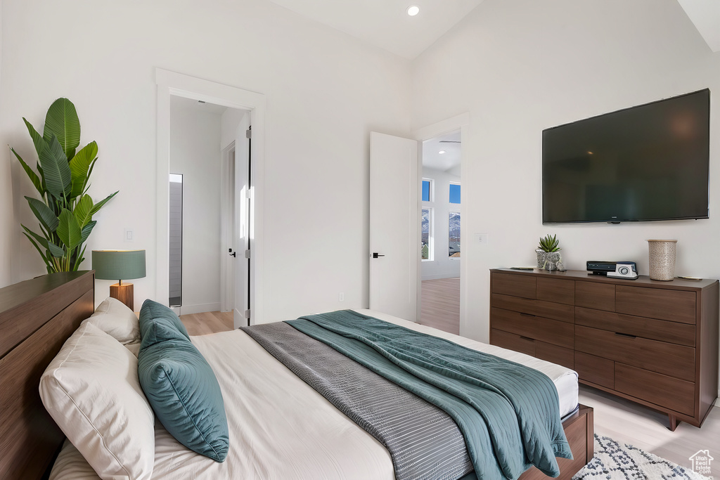 Bedroom with ensuite bathroom, vaulted ceiling, and light hardwood / wood-style flooring