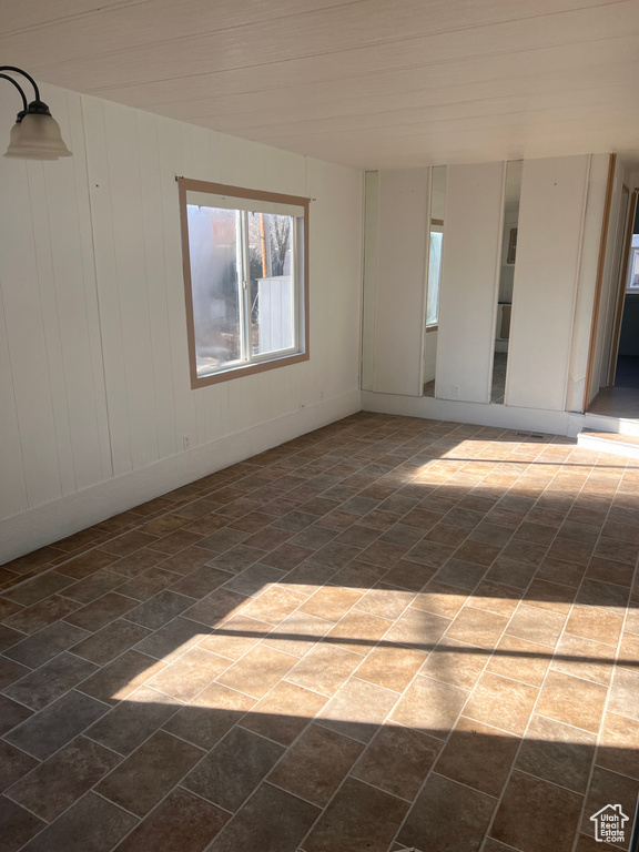 Unfurnished room featuring wooden walls