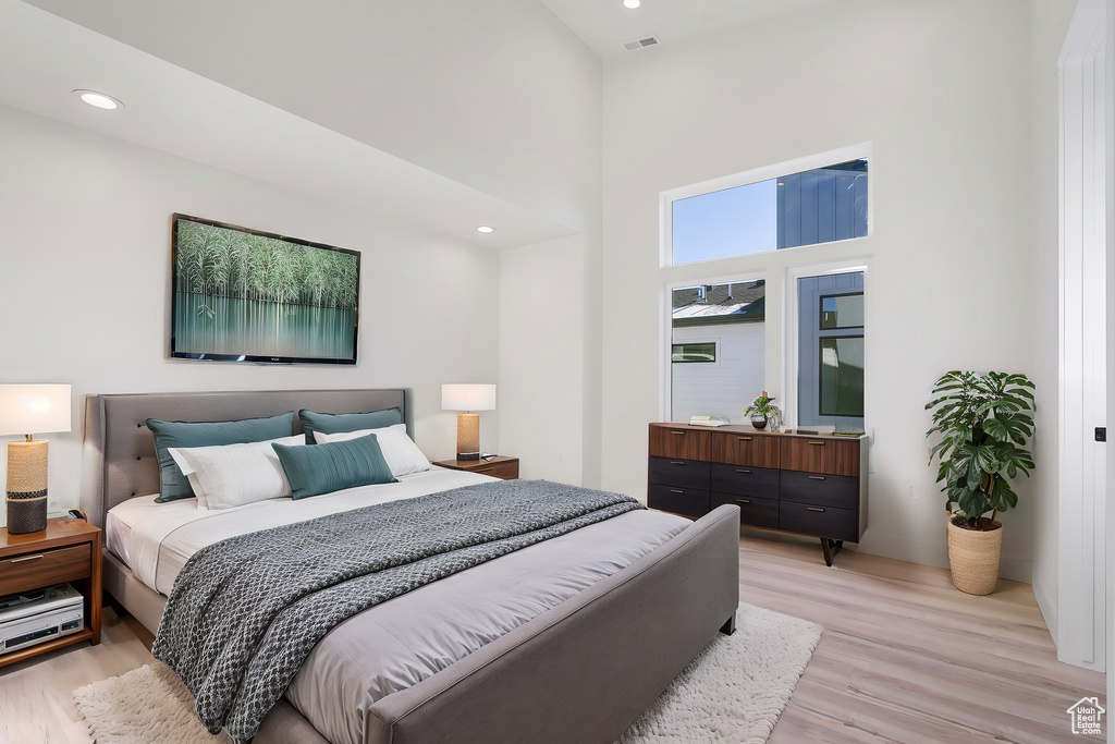 Bedroom with a towering ceiling and light hardwood / wood-style flooring